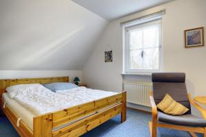 a bedroom with a bed and a chair and a window at Waldesruh - App2 in Zingst