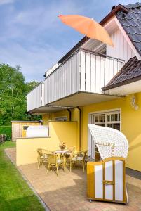 a yellow house with a table and chairs and an umbrella at Gotland 2 in Zingst