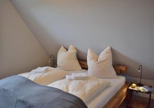 2 Betten mit weißer Bettwäsche und Kissen in einem Zimmer in der Unterkunft Reethaus 4B in Staberdorf