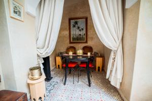 een tafel en stoelen in een kamer met gordijnen bij Riad Inaka in Marrakesh