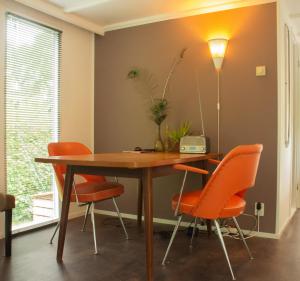 een eetkamer met een tafel en oranje stoelen bij FoREST in Zuidlaren