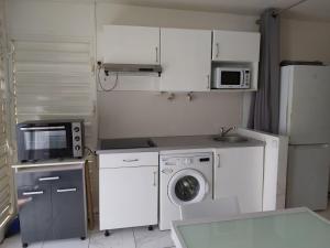 a kitchen with a washing machine and a microwave at ANSE DES ROCHERS St François CORAIL 306 in Saint-François