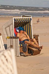 ヴァンガーオーゲにあるOsterdüne 63の浜辺の椅子に横たわる男