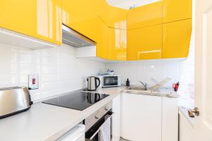 eine Küche mit weißen Arbeitsflächen und gelben Schränken in der Unterkunft Holiday Beach Flat in Bournemouth, England, UK in Bournemouth