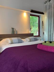 a bedroom with a large bed with purple sheets and a window at Hacienda de la Canopée avec piscine chauffée au sel in Hourtin +23 photos