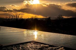 um pôr do sol sobre um corpo de água com o pôr do sol em Villa Le Prata - Farm House & Winery - Adults Only em Montalcino