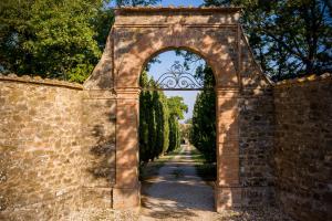 une arche sur un mur de briques avec des arbres dans l'établissement Villa Le Prata - Farm House & Winery - Adults Only, à Montalcino