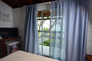 a bedroom with a window with a blue curtain at Villa dos Ganchos in Governador Celso Ramos