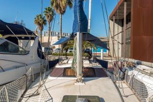 un barco atracado en un puerto deportivo con palmeras en Pequeño velero en Port Forum ideal para Backpackers en Barcelona