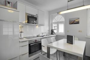 a kitchen with white appliances and a white table at Villa Obendtied, FW 3 in Zingst