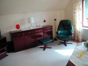 een woonkamer met een groene stoel, een bureau en een lamp bij Frauke Bruhn in Fockbek