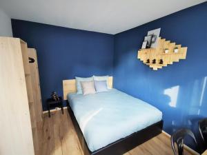 Dormitorio azul con cama y pared azul en Chez Jo, en Lens