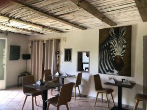 a dining room with tables and a picture of a zebra at Restaurant et Chambres d'Hôtes La Ferme de Cornadel in Anduze