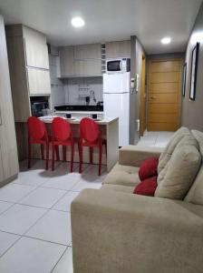 een woonkamer met een bank en rode stoelen in een keuken bij Estudio Confort West Flat com ótima localização. in Mossoró