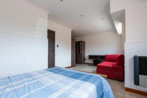 ein Schlafzimmer mit einem Bett und einem roten Stuhl in der Unterkunft ApartKhozama in Camet Norte