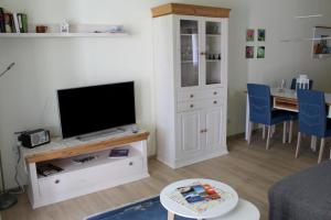a living room with a flat screen tv and a table at Seeschwalbe App 34 in Dierhagen
