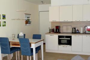 a kitchen with white cabinets and a table and blue chairs at Seeschwalbe App 34 in Dierhagen