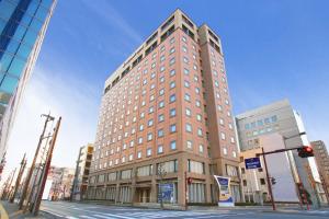 un edificio alto en la esquina de una calle de la ciudad en President Hotel Mito, en Mito