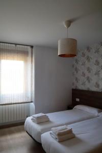 - une chambre avec 2 lits et une fenêtre avec des serviettes dans l'établissement Apartamento CATA Santiago de Compostela, à Saint-Jacques-de-Compostelle