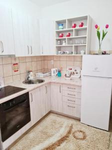 Elle comprend une petite cuisine avec des placards blancs et un évier. dans l'établissement Apartman Sky, à Bijeljina