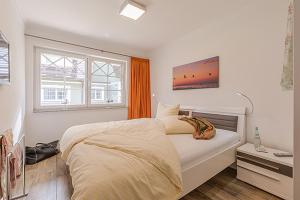 a white bedroom with a bed and a window at Les Belles, Haus Bastien, FW Charmant, Whg 7 in Zingst