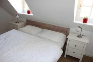 a bedroom with a white bed and two night stands at Reethus WE 2, Föhrkiek in Borgsum