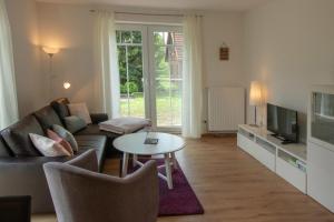 a living room with a couch and a tv and a table at Huxfeld-Hof - Landliebe in Grasberg