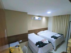 ein Hotelzimmer mit 2 Betten und einem Tisch in der Unterkunft Hotel Encanto do Sertão in Triunfo
