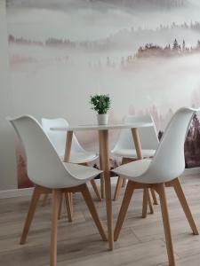 stół i 4 białe krzesła w pokoju w obiekcie Apartament w Polanicy w Polanicy Zdroju