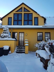 una casa gialla con la neve davanti di Attraktive FeWo in Rosenthal am Rennsteig a Neundorf