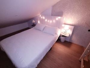 ein Schlafzimmer mit einem weißen Bett mit Beleuchtung in der Unterkunft Adorelys week end massage et spa in Saint-Cassien
