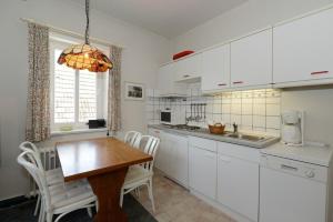 eine Küche mit weißen Schränken und einem Holztisch in der Unterkunft Haus Poggfred Whg 06 Swan in Wyk auf Föhr