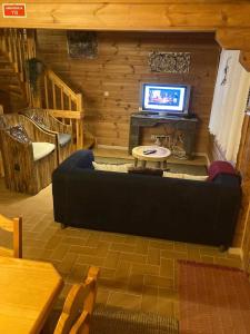 a living room with a couch in front of a tv at Chalé 41 in Cortes do Meio