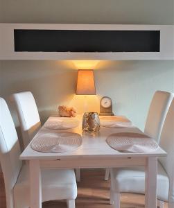 einen weißen Tisch mit Stühlen und eine Lampe drauf in der Unterkunft Domizil an der Huysburg in Dingelstedt