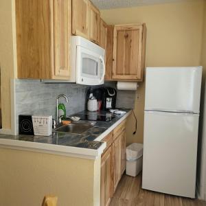 een keuken met een witte koelkast en houten kasten bij Oceanfront Escape With Balcony and heated salt water pool! in Daytona Beach