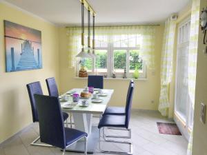 a dining room with a white table and blue chairs at Haus Kathrin in Zingst