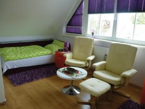 1 Schlafzimmer mit einem Bett, 2 Stühlen und einem Tisch in der Unterkunft Haus Kathrin in Zingst