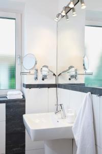 ein weißes Badezimmer mit einem Waschbecken und Spiegeln in der Unterkunft Strandläufer - 29764 in Haffkrug