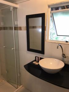 uma casa de banho com um lavatório e uma cabina de duche em vidro. em Pousadinha na Ilha do Mel