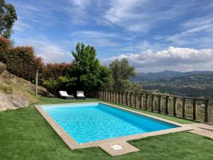 a swimming pool in the middle of a lawn with two chairs at Casa do Caminho do Monte in Arcos de Valdevez