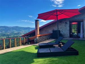 una persona sentada en una silla bajo un paraguas rojo en Casa do Caminho do Monte en Arcos de Valdevez