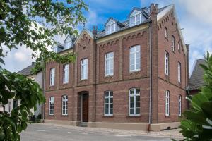 - un grand bâtiment en briques rouges avec des fenêtres blanches dans l'établissement Römer-Apartment im Herenhaus Rheinblick, à Xanten