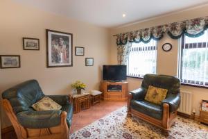 a living room with two chairs and a tv at Drumgart Self Catering Cottage in Carrickfergus