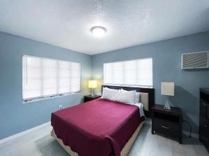 a bedroom with a bed with a purple blanket and two windows at Sunrise Resort Motel South in Clearwater Beach +102 photos
