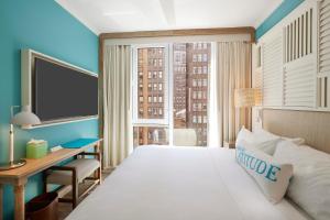 a hotel room with a bed and a desk and a large window at Margaritaville Resort Times Square in New York