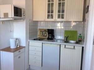 uma pequena cozinha com armários brancos e um lavatório em Neue Straße 3 em Grossenbrode