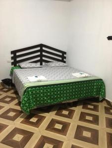 a bed in a room with a green comforter at Hotel Aruma in El Remate