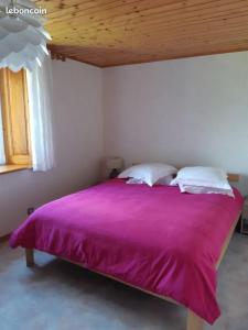 1 dormitorio con cama morada y techo de madera en Gîte La petite maison horlogère et jacuzzi , raquettes en Les Fontenelles