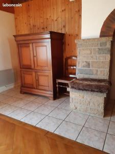 a room with a wooden cabinet and a stone fireplace at Gîte La petite maison horlogère et jacuzzi , raquettes in Les Fontenelles