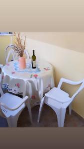 a table with two white chairs and a bottle of wine at Katarina in Bijela